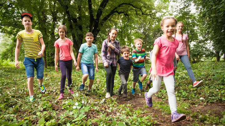 Viele Kinder wandern lachend durch ein Waldgebiet | © Oksix / Adobe Stock